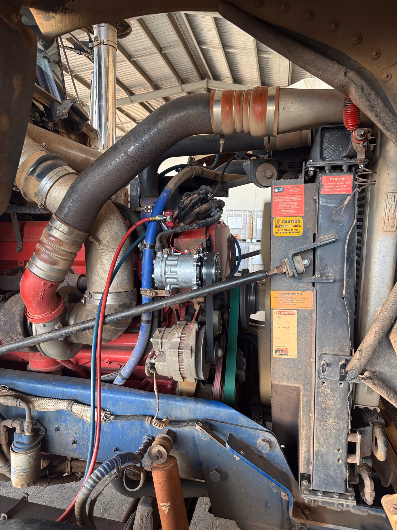 Air conditioning compressor and lines on a heavy truck diesel engine, with the cab tilted forward