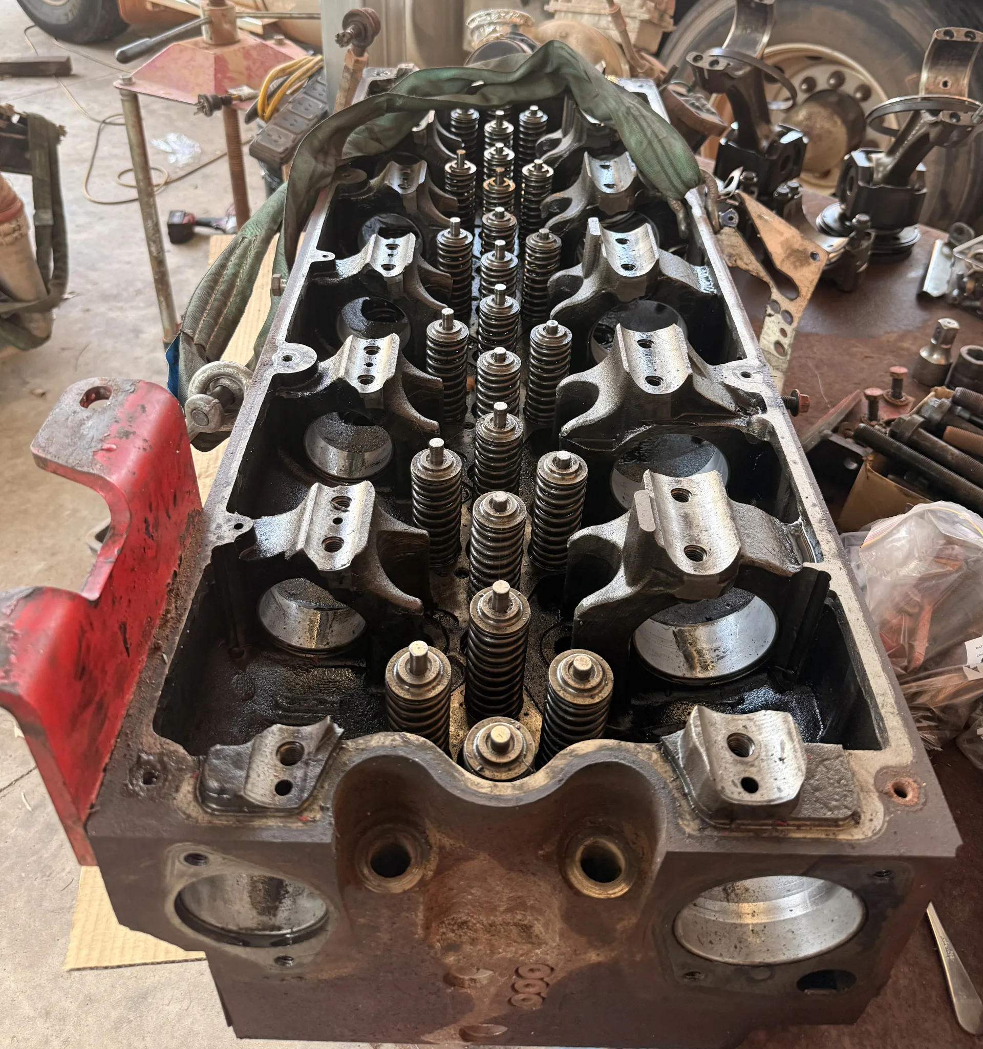 Diesel cylinder head stripped down on the bench, with valve springs exposed mid rebuild