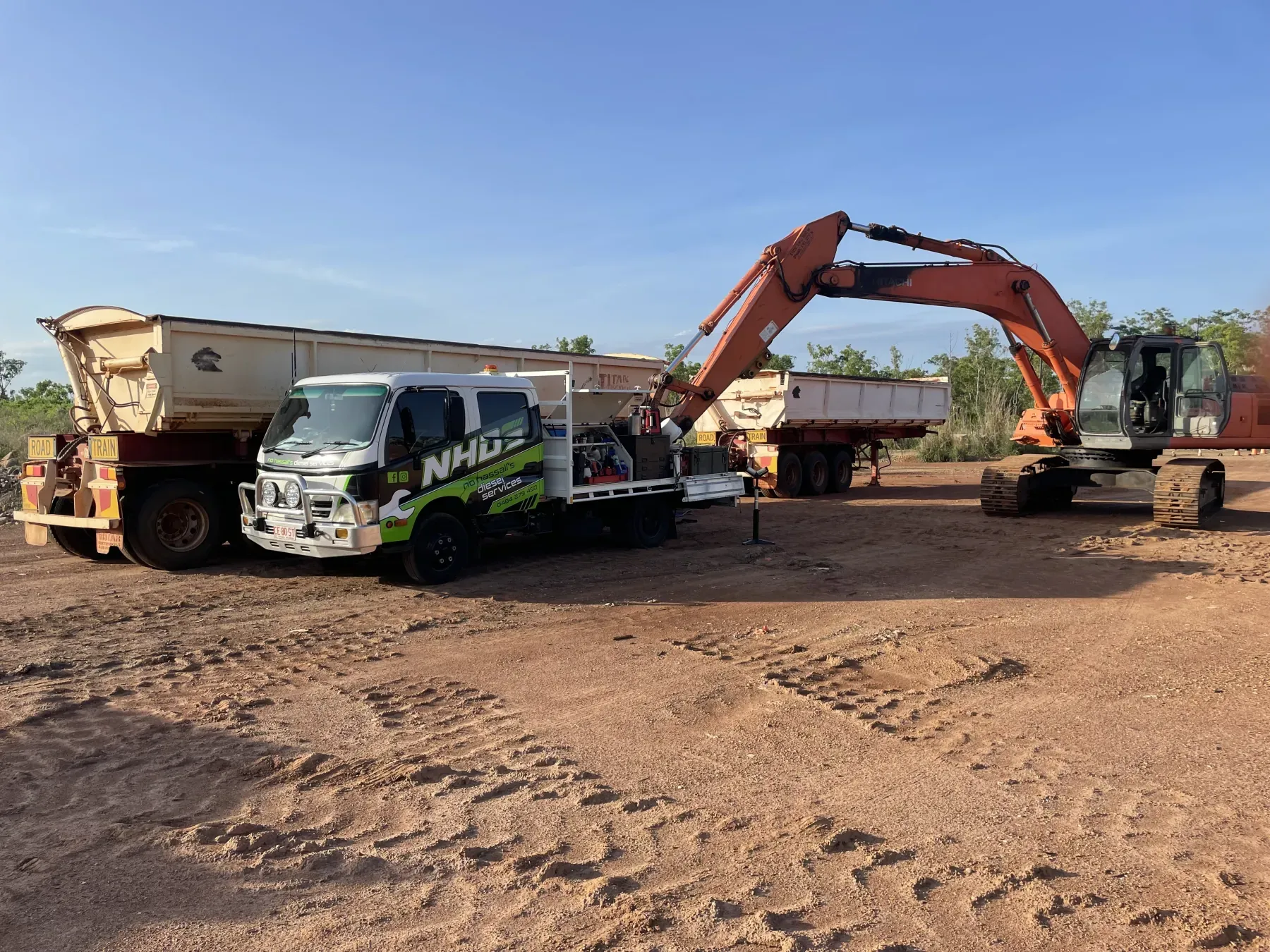 NHDS service truck set up beside an excavator and side tipper trailers on a red dirt civil site