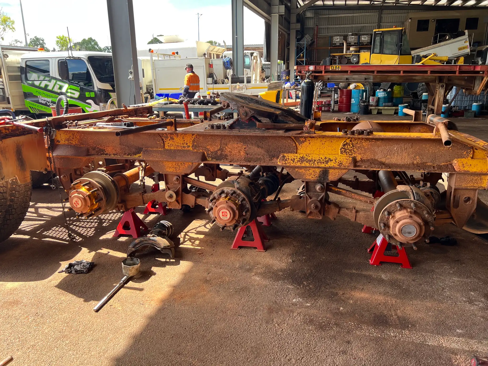 Heavy truck chassis on stands mid rebuild, with the NHDS truck behind